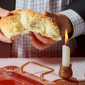 Sabbath kiddush ceremony composition with two wax candles in candlesticks and a traditional sweet